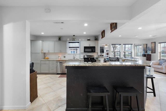 kitchen featuring tasteful backsplash, stainless steel appliances, light tile patterned floors, gray cabinets, and a breakfast bar area