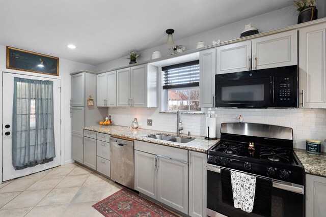 kitchen with light stone countertops, backsplash, gray cabinetry, stainless steel appliances, and sink