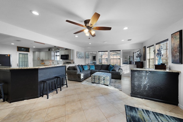 living room with light tile patterned floors, ceiling fan, and sink