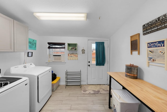 laundry area featuring washing machine and clothes dryer, cabinets, cooling unit, light hardwood / wood-style floors, and a textured ceiling