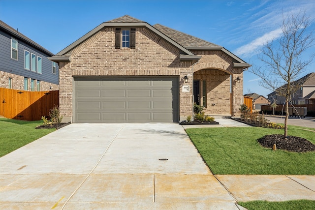 french country style house featuring brick siding, a front lawn, fence, concrete driveway, and a garage