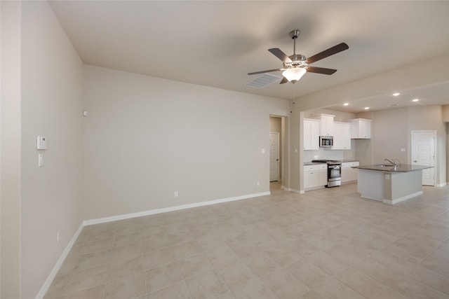 interior space featuring sink, white cabinetry, a center island with sink, appliances with stainless steel finishes, and ceiling fan