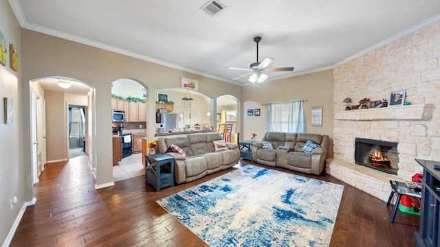 living room featuring a fireplace, ceiling fan, crown molding, and dark hardwood / wood-style flooring