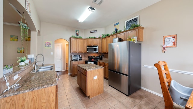 kitchen featuring dark stone counters, sink, light tile patterned floors, appliances with stainless steel finishes, and kitchen peninsula