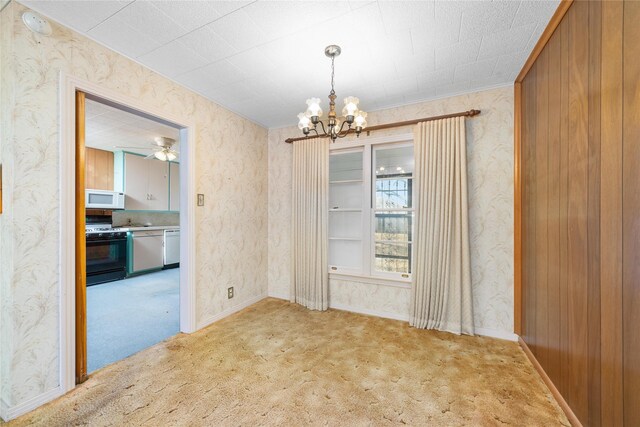 unfurnished dining area featuring carpet flooring, wood walls, and a chandelier