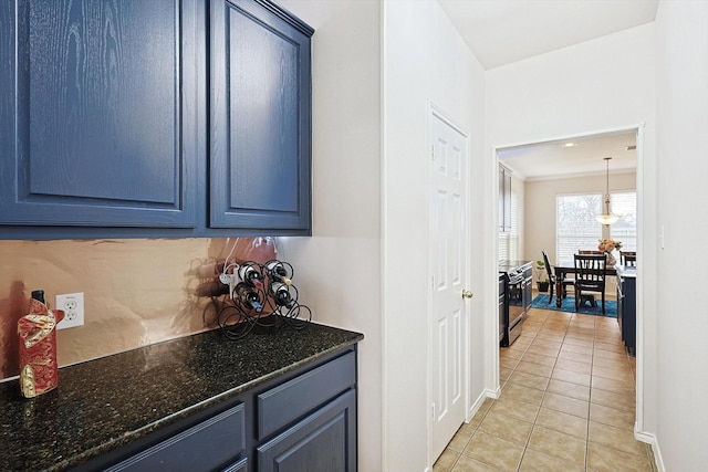 kitchen with dark stone countertops, blue cabinets, light tile patterned flooring, and baseboards