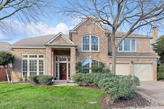 traditional-style house with a front yard, driveway, an attached garage, a chimney, and brick siding