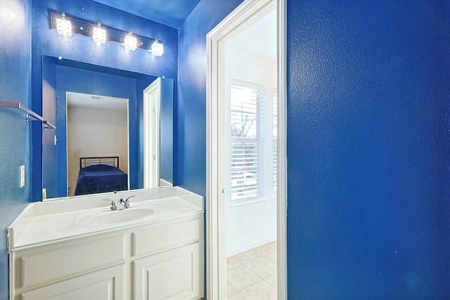 ensuite bathroom with vanity, baseboards, ensuite bathroom, tile patterned floors, and a textured wall