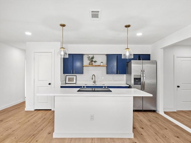 kitchen with light countertops, stainless steel fridge, a sink, and blue cabinetry