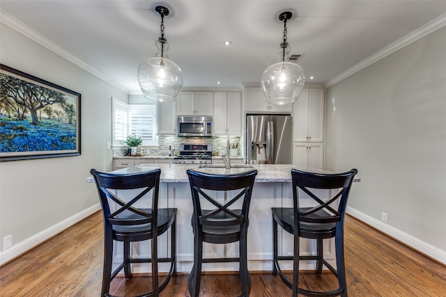 kitchen featuring pendant lighting, light stone countertops, white cabinetry, and stainless steel appliances