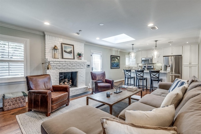 living room featuring a fireplace, a skylight, light hardwood / wood-style flooring, and plenty of natural light