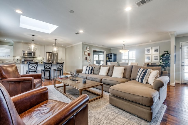 living room featuring light wood-type flooring, a skylight, and ornamental molding