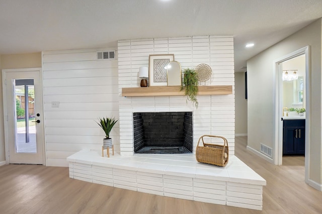 unfurnished living room featuring light wood-type flooring and a brick fireplace