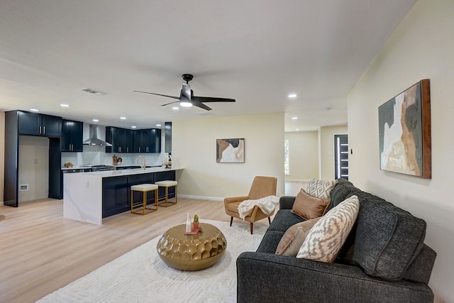 living room featuring ceiling fan, sink, and light hardwood / wood-style flooring