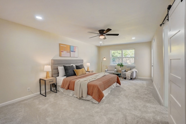 carpeted bedroom featuring ceiling fan and a barn door