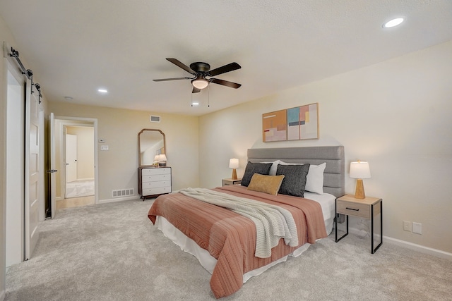 carpeted bedroom with ceiling fan and a barn door