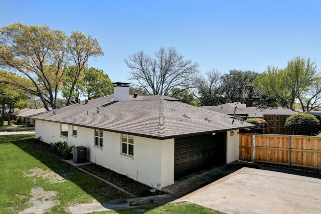 rear view of house with central AC unit and a lawn