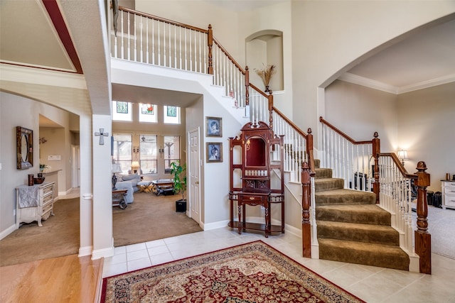 tiled foyer entrance featuring crown molding and a high ceiling