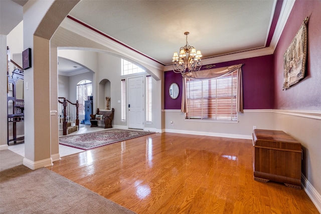 foyer with hardwood / wood-style floors, ornamental molding, and a notable chandelier