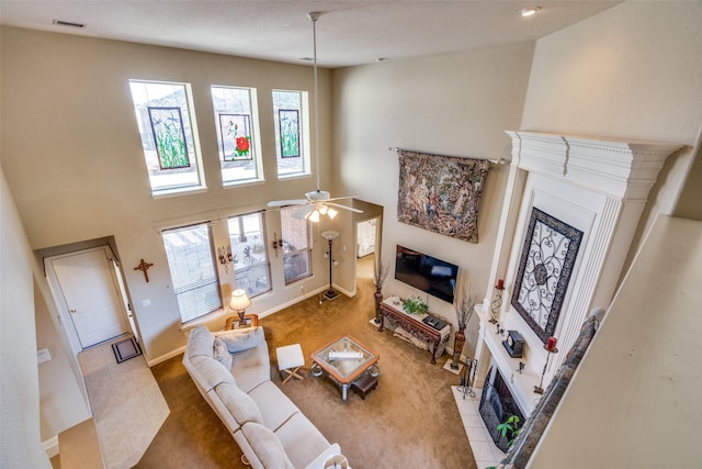 tiled living room with a fireplace, a towering ceiling, and ceiling fan