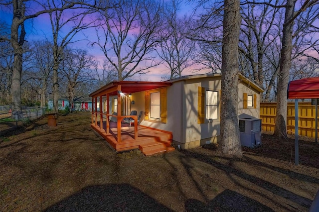 property exterior at dusk with central AC and a deck