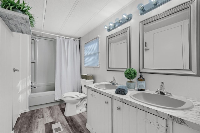 full bathroom with vanity, hardwood / wood-style flooring, toilet, shower / bath combo with shower curtain, and a textured ceiling