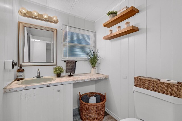 bathroom featuring hardwood / wood-style floors, vanity, toilet, and wooden walls