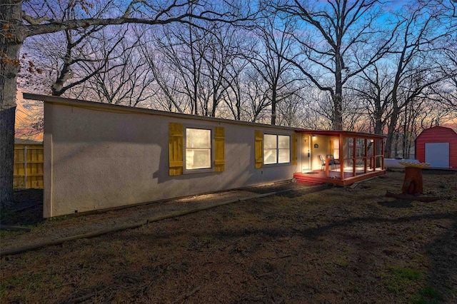 back house at dusk with a storage shed and a wooden deck