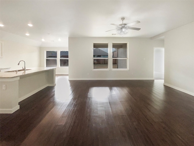 unfurnished living room featuring dark hardwood / wood-style flooring, ceiling fan, and sink