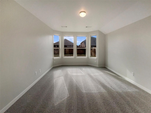 carpeted spare room with vaulted ceiling