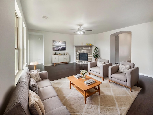 living room featuring ceiling fan, a fireplace, and light wood-type flooring