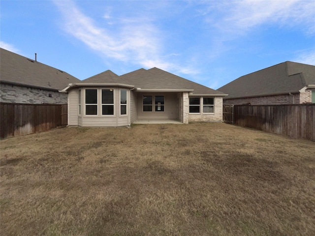 back of property with a yard and a patio area