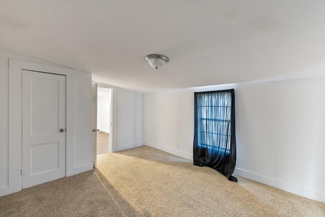 carpeted spare room featuring vaulted ceiling