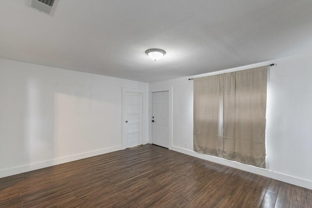 empty room with a textured ceiling and dark hardwood / wood-style floors