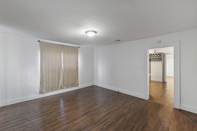 empty room with dark wood-type flooring and a textured ceiling