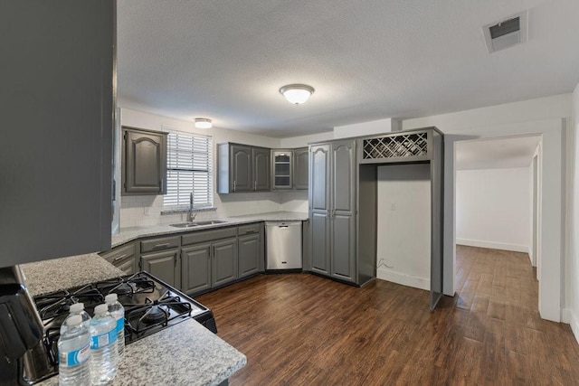 kitchen featuring gray cabinetry, sink, stainless steel dishwasher, and light stone countertops