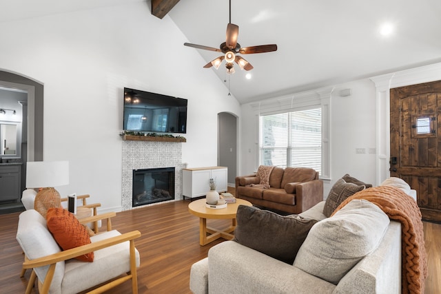 living room with a fireplace, ceiling fan, dark hardwood / wood-style flooring, and vaulted ceiling with beams