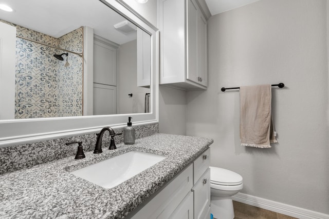 bathroom featuring a tile shower, vanity, and toilet