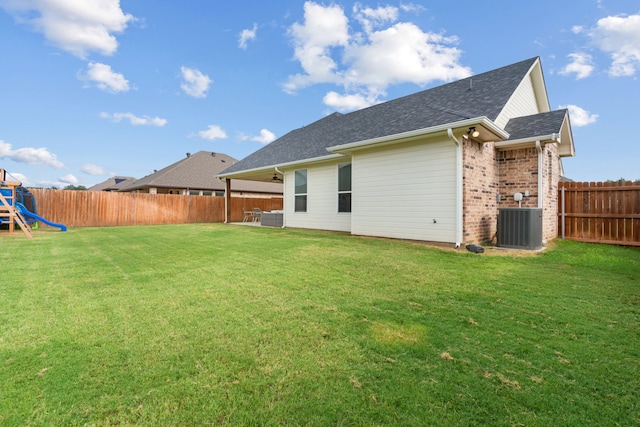 back of property featuring a playground, a yard, and central AC unit