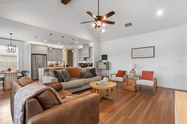 living room with sink, beamed ceiling, high vaulted ceiling, wood-type flooring, and ceiling fan with notable chandelier