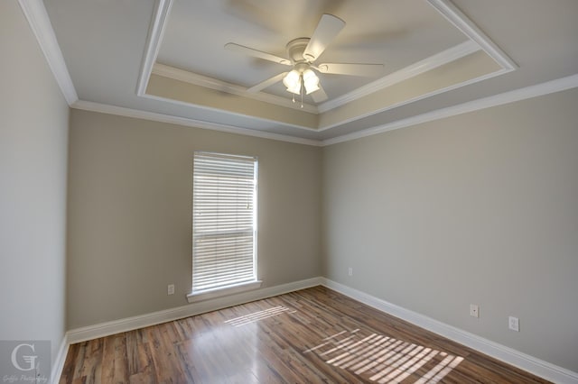 empty room with ceiling fan, ornamental molding, a raised ceiling, and hardwood / wood-style floors