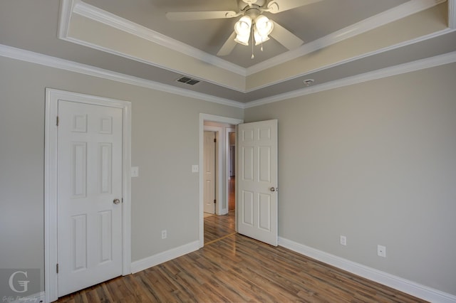 unfurnished bedroom featuring crown molding, ceiling fan, wood-type flooring, and a tray ceiling