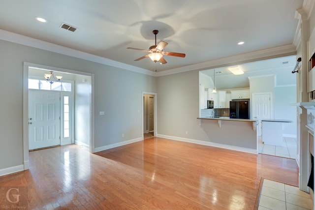 unfurnished living room with ceiling fan with notable chandelier, light wood-type flooring, ornamental molding, and a tile fireplace