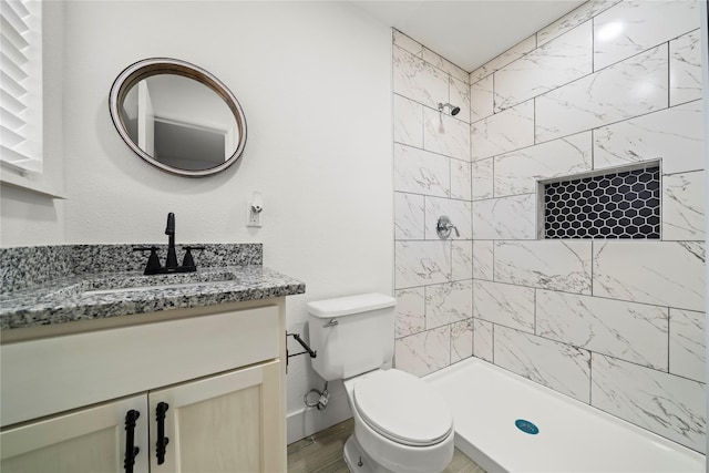 bathroom with vanity, toilet, wood-type flooring, and a tile shower