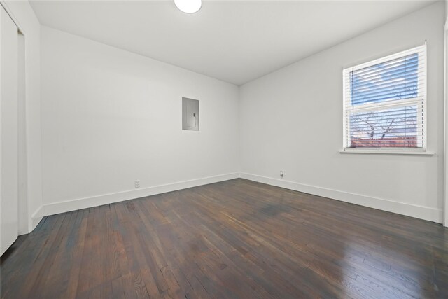 spare room featuring electric panel and dark hardwood / wood-style flooring