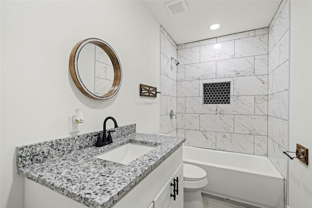 full bathroom featuring tiled shower / bath, vanity, and toilet