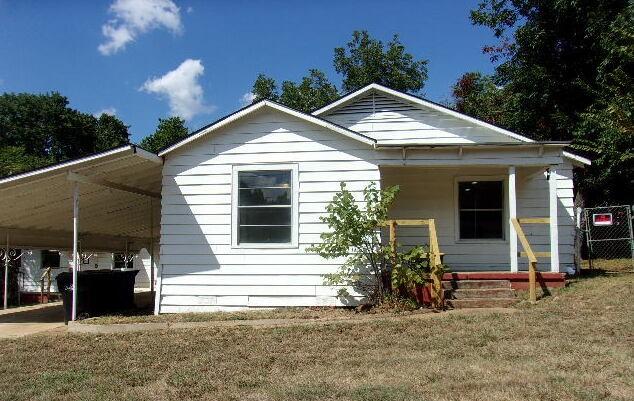 rear view of property with a lawn and a carport