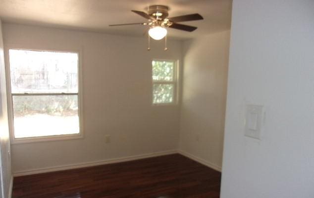 unfurnished room featuring plenty of natural light, ceiling fan, and dark wood-type flooring