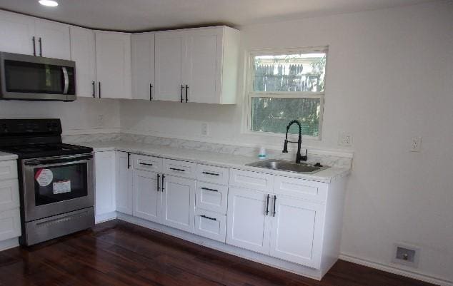 kitchen featuring stainless steel appliances, white cabinetry, and sink