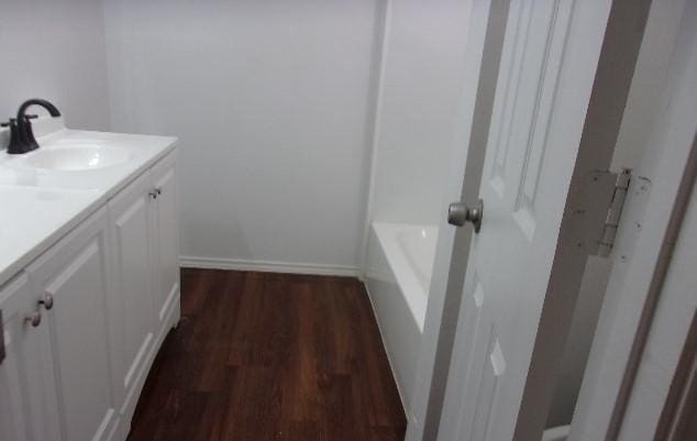 bathroom with hardwood / wood-style floors, vanity, and a washtub